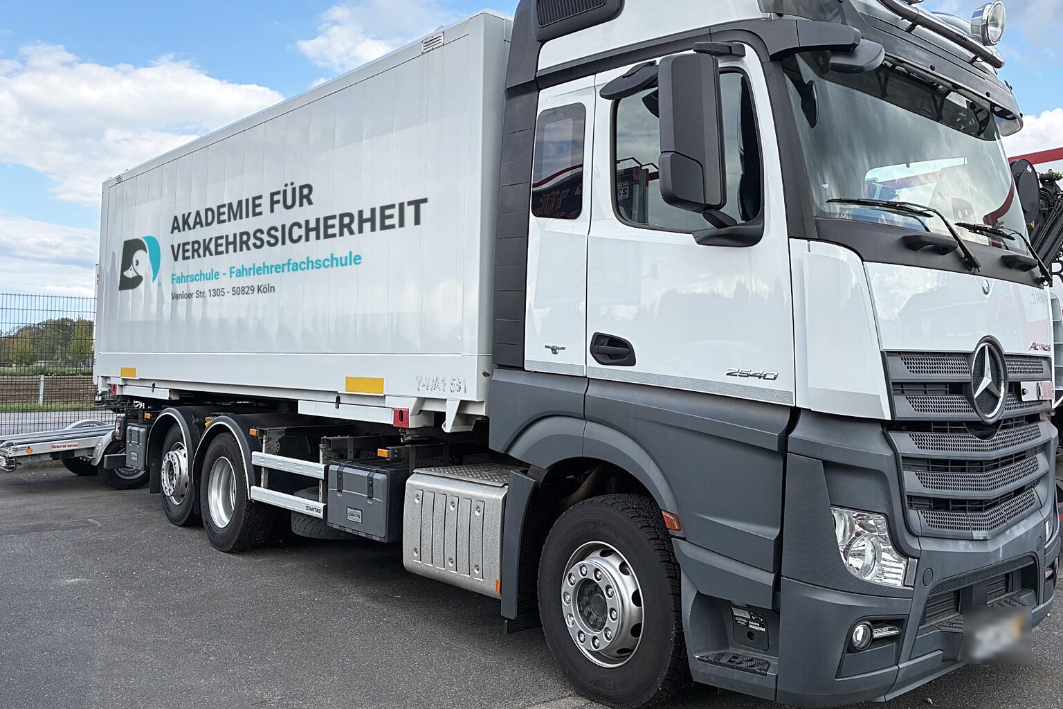 Lastwagen auf einem Hof, auf dem Aufbau der Schriftzug Akademie für Verkehrssicherheit, Fahrschule und Fahrlehrerfachschule