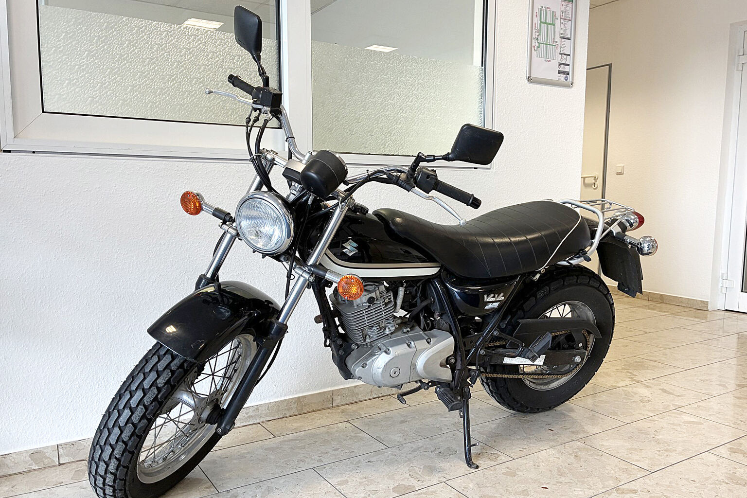 Motorrad auf dem Seitenständer in einem gefliesten Flur